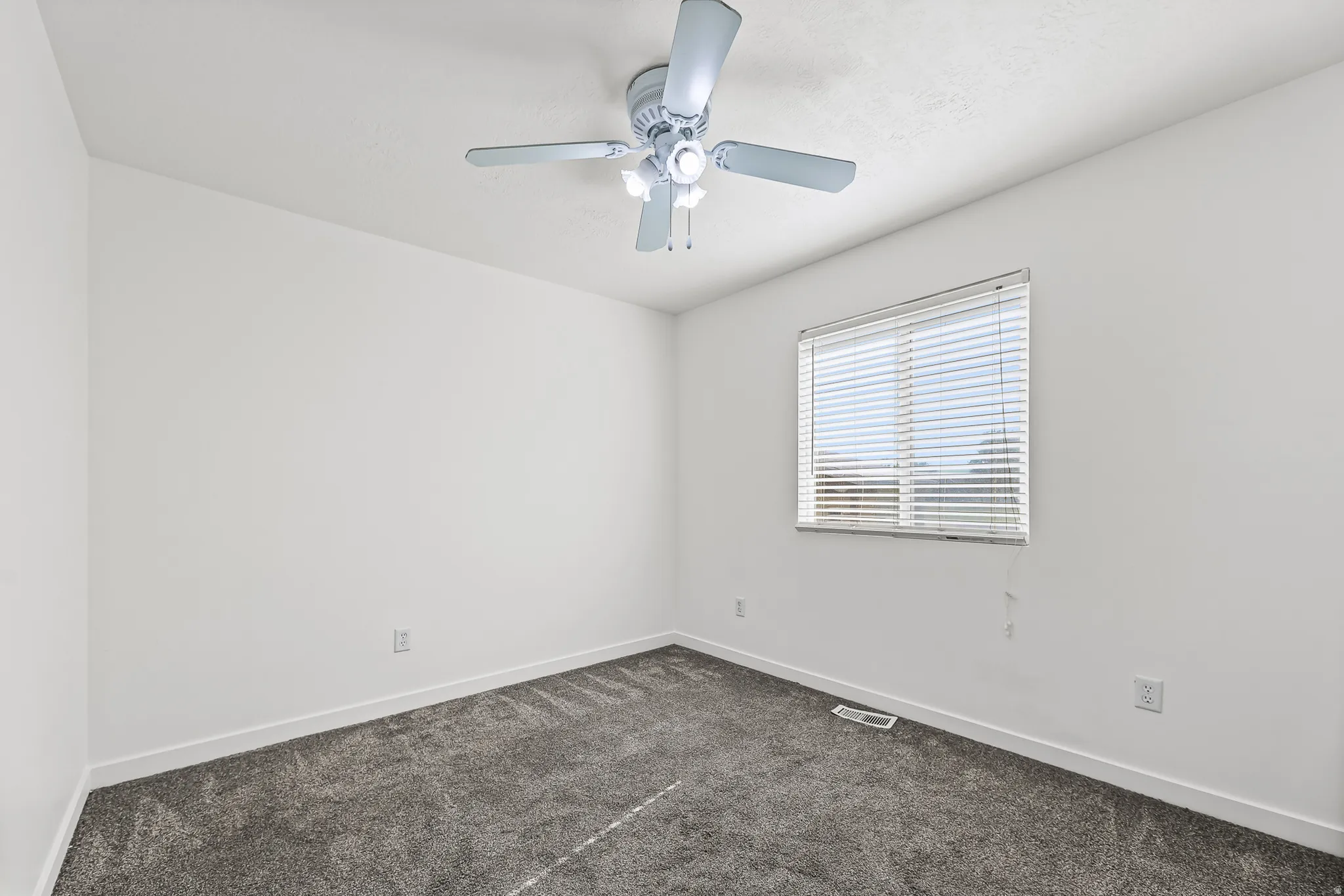 Carpeted room featuring a ceiling fan with integrated lighting, a single window with blinds, and white painted walls