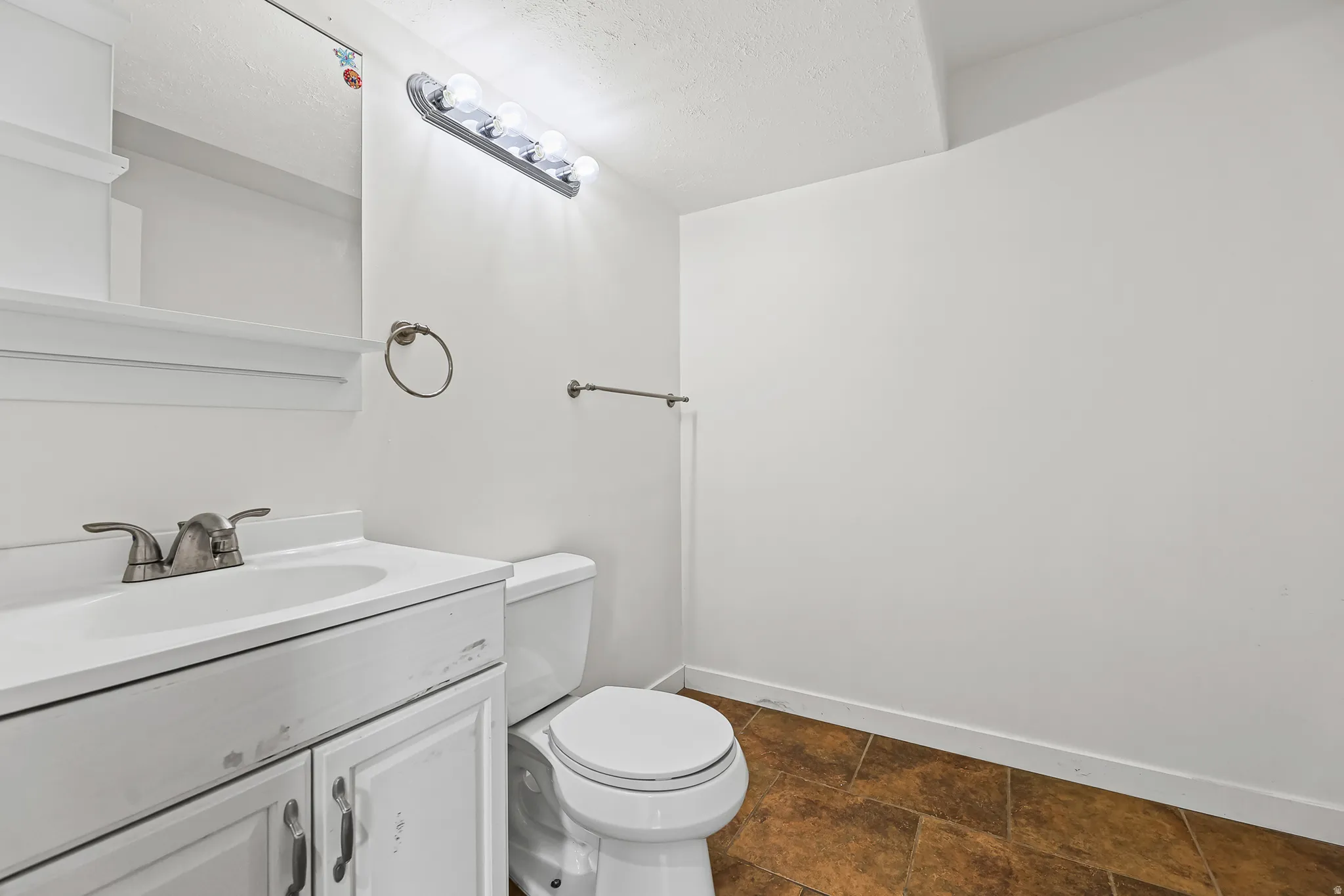 Bathroom featuring a white vanity with integrated sink, brushed nickel faucet, and a wall-mounted mirror