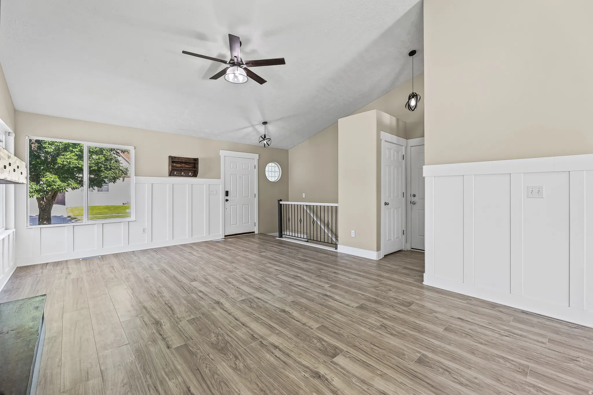 Spacious interior featuring wood-finish flooring, vaulted ceilings, and board and batten wainscoting