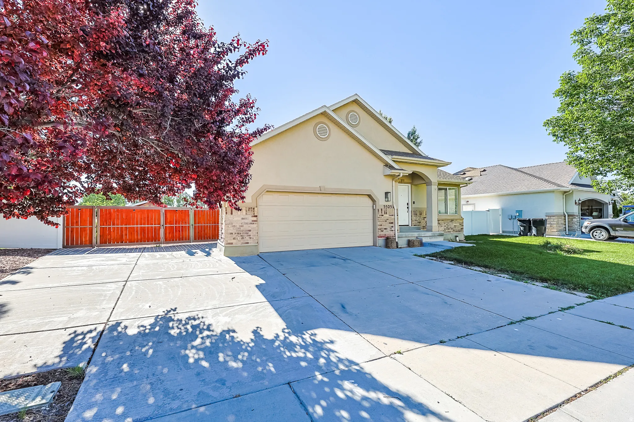 Exterior showcasing a neutral stucco finish with stone accents, a two-car garage, and a concrete driveway