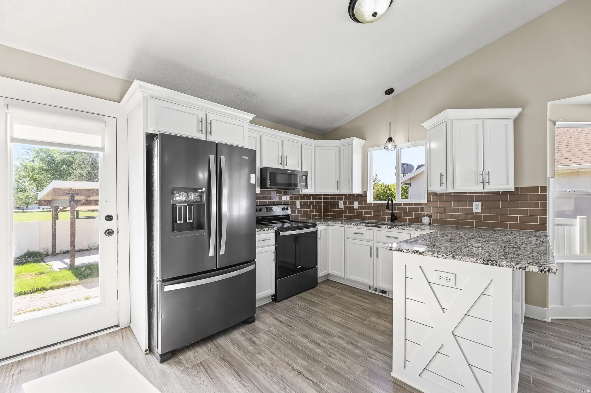 Modern kitchen featuring white cabinetry, a brown subway tile backsplash, and wood-finish flooring