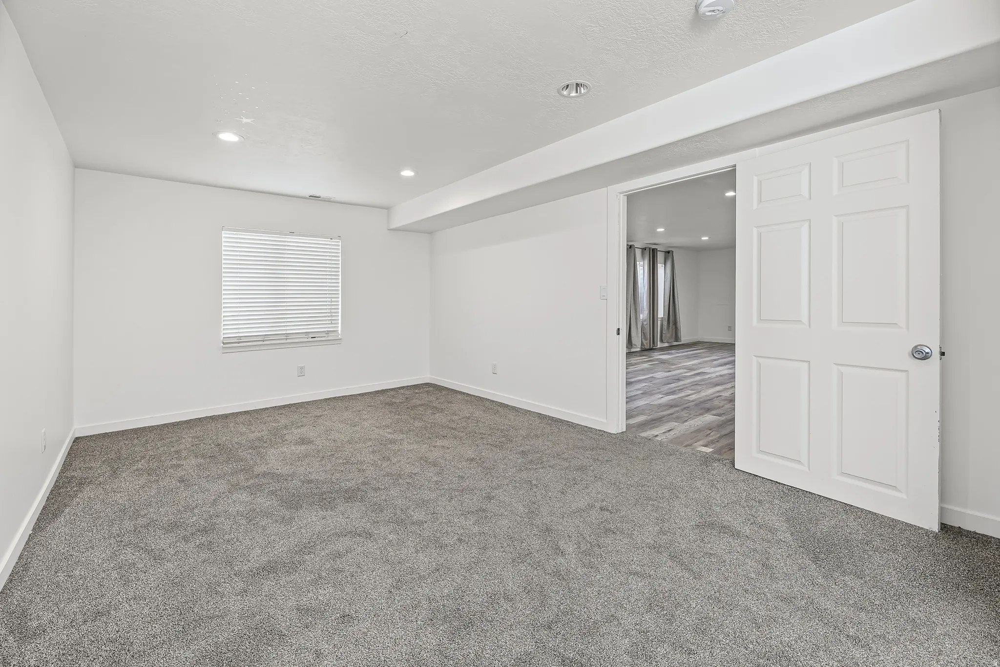 Spacious room with gray carpet flooring and recessed lighting