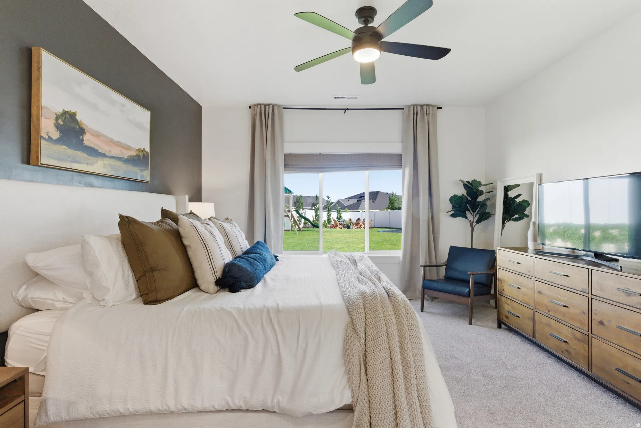 Carpeted room with a large window, a ceiling fan with integrated lighting, and a dark accent wall