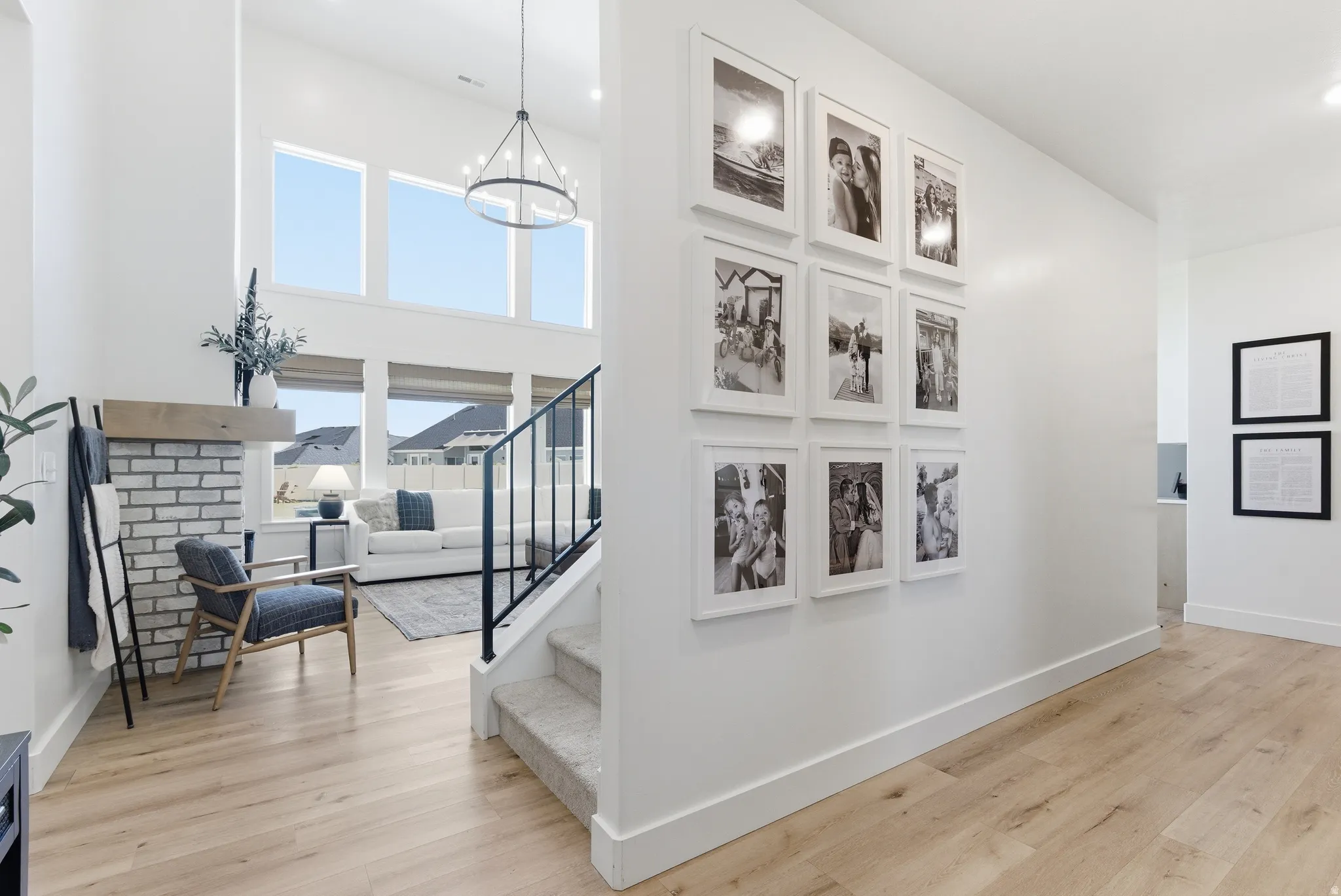Two-story entry featuring light wood-finish flooring, a contemporary chandelier, and an open staircase with black metal railings