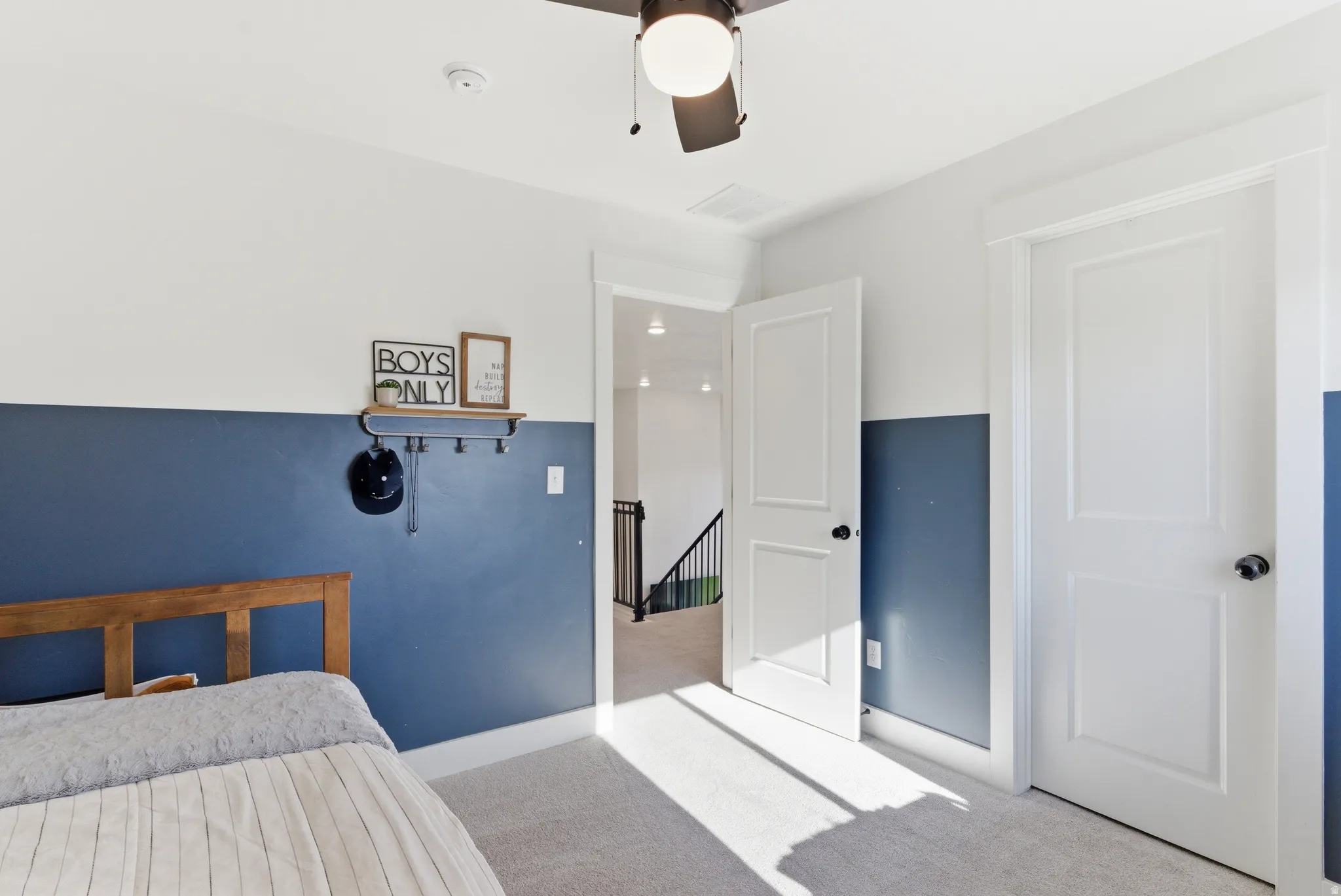 Carpeted room featuring a ceiling fan with integrated lighting, two-tone painted walls, and white paneled doors with black hardware