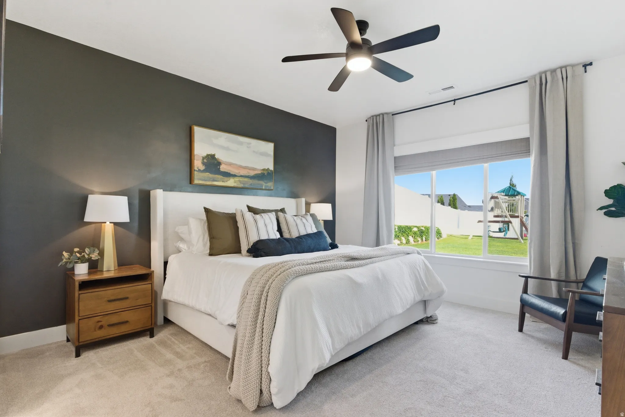 Bedroom featuring a dark accent wall, a large window, a modern ceiling fan with lighting, and light-colored carpeting