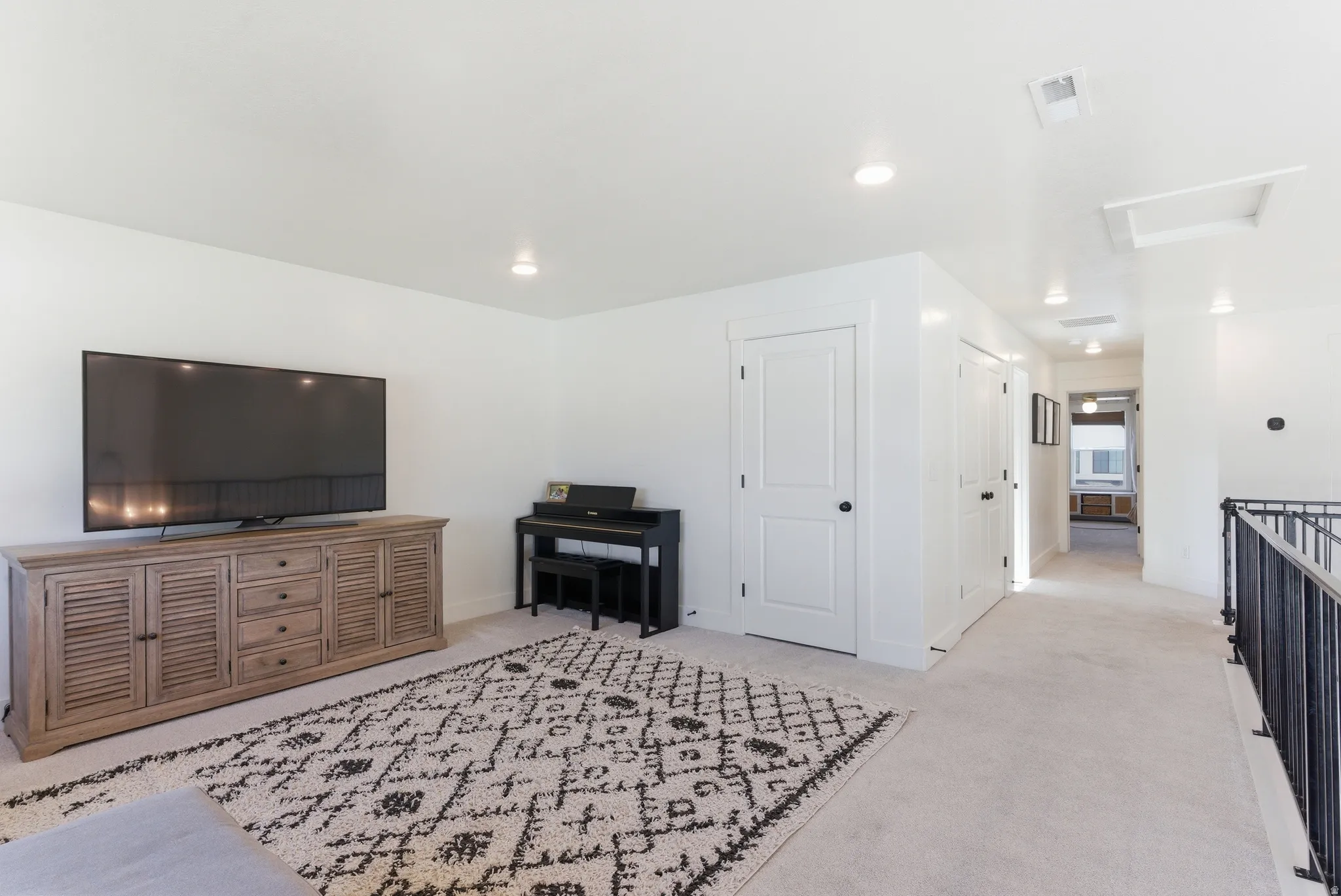Carpeted entertainment area featuring recessed lighting, white walls, and white doors with dark hardware
