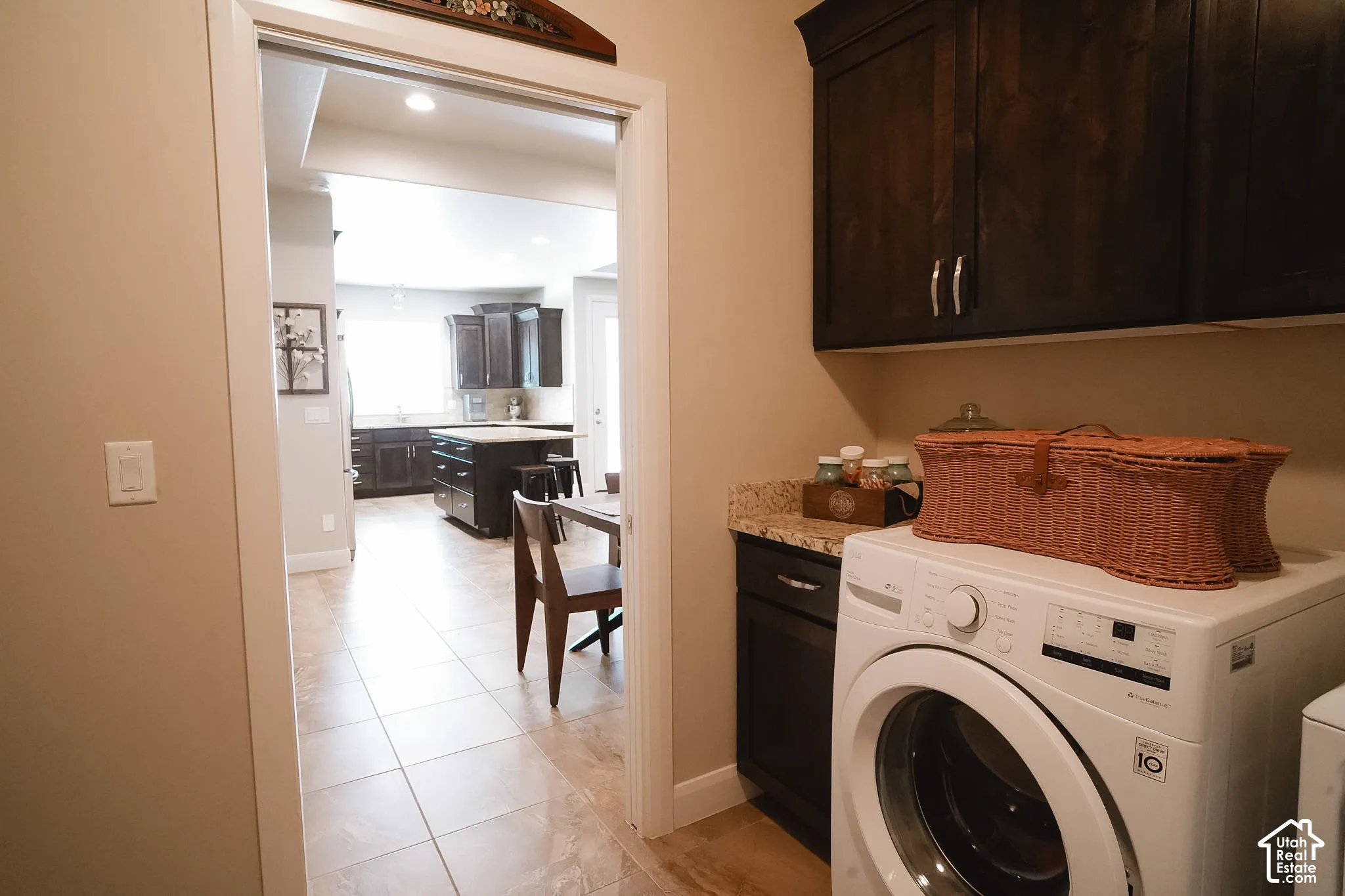 Laundry area featuring dark wood-finish cabinetry, a light-colored solid surface countertop, and tiled flooring