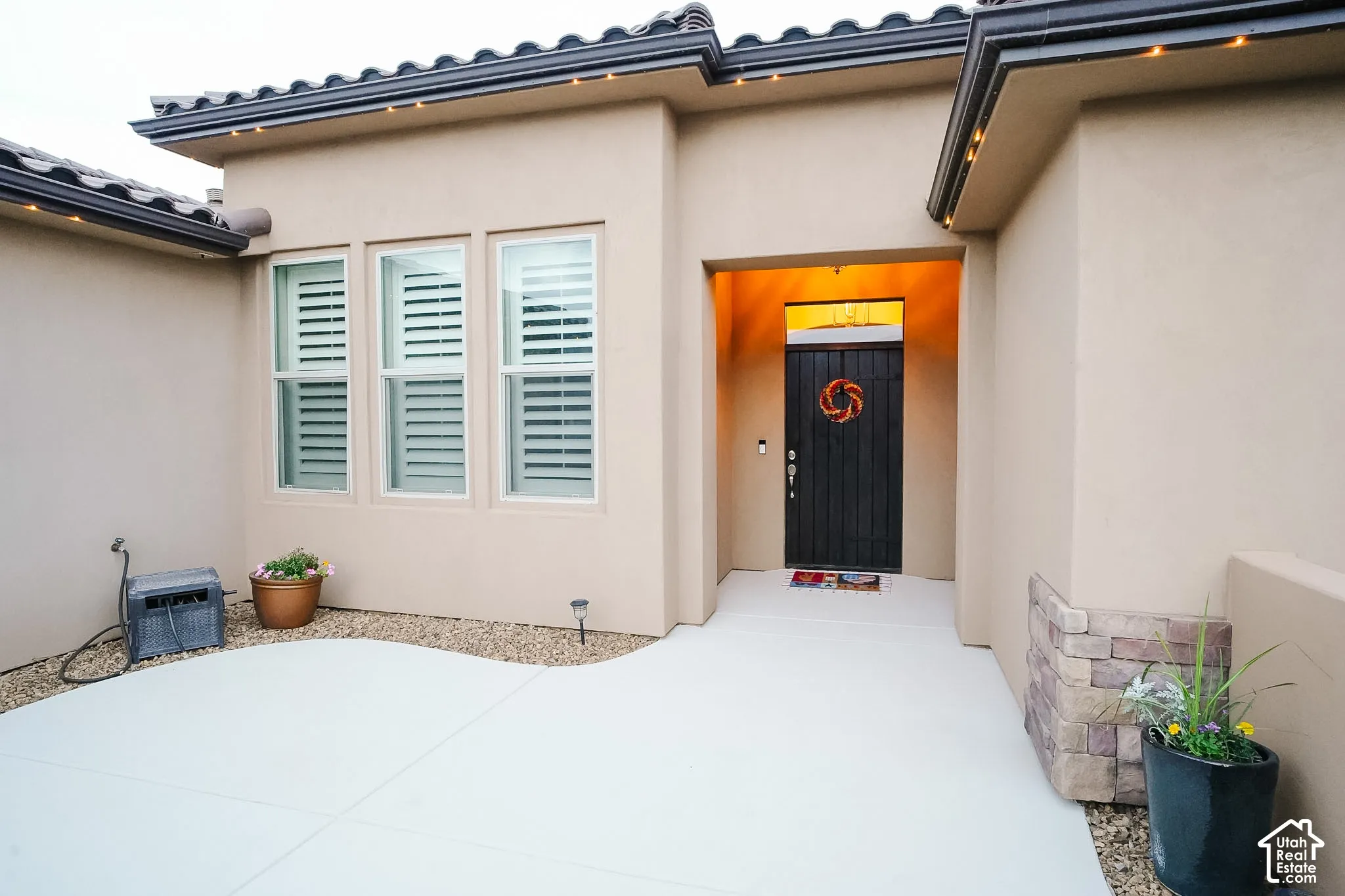 Entryway featuring stucco exterior, tiled roofline, and a dark wood-paneled front door
