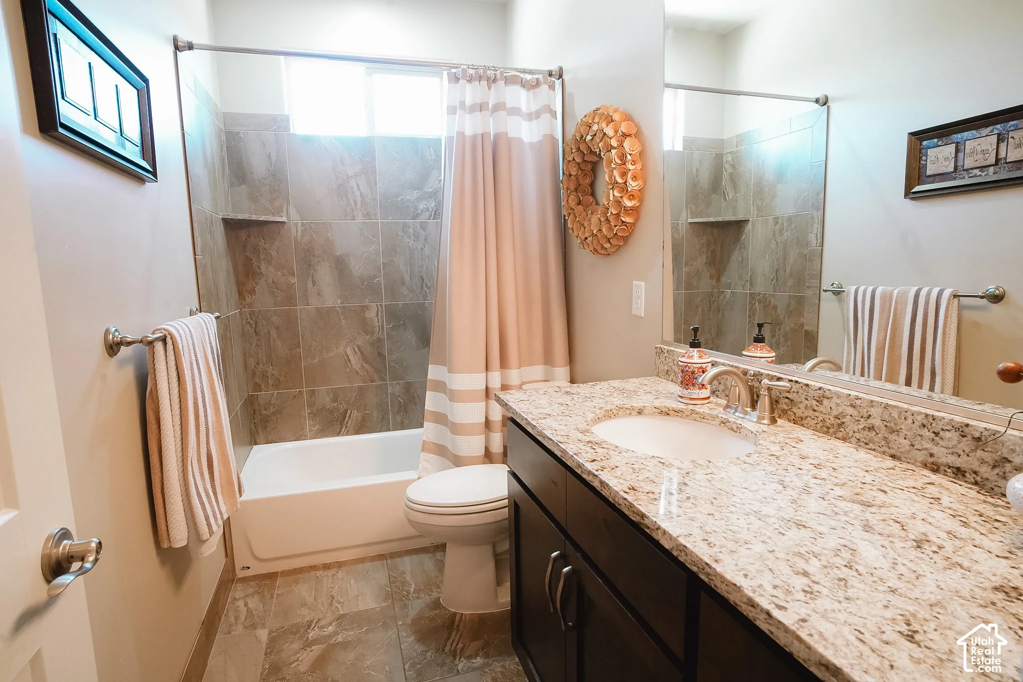 Bathroom featuring a granite countertop vanity with an undermount sink, dark wood-finish cabinetry, and a full-width mirror