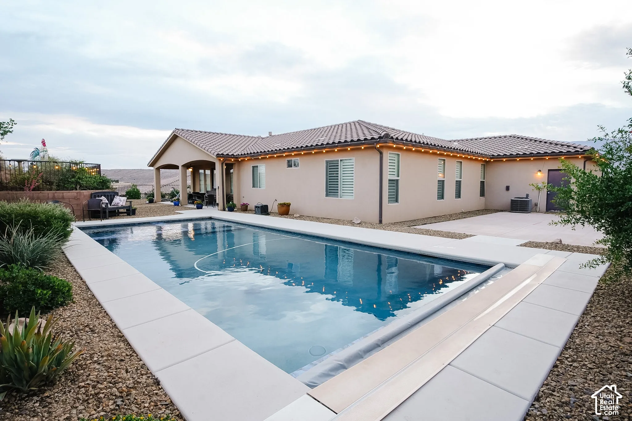 Outdoor swimming pool with a concrete surround, surrounded by a gravel landscape and low-lying desert vegetation