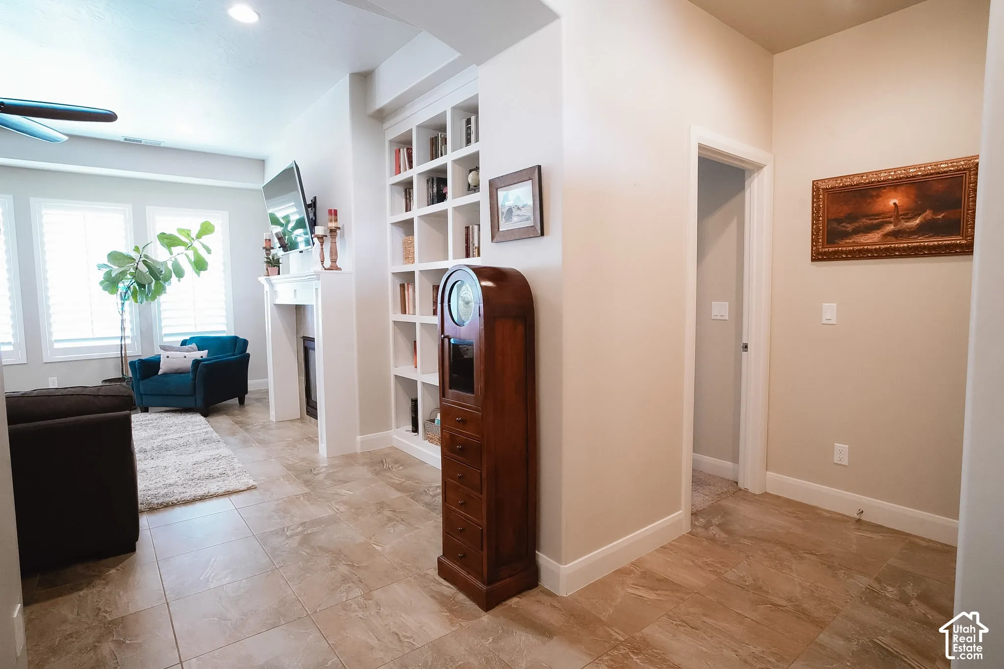 Living area featuring tile flooring, built-in shelving, a fireplace with a mantel, multiple windows with plantation shutters, and recessed lighting