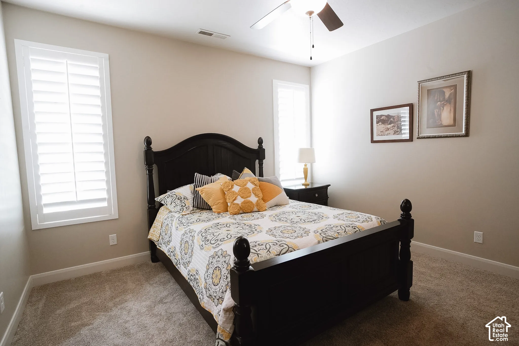 Carpeted room featuring two windows with white plantation shutters