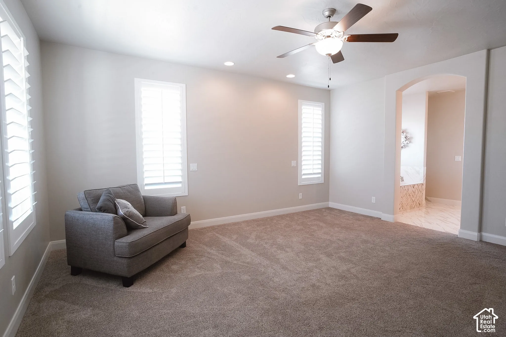 Spacious room featuring neutral carpeting, recessed lighting, and a ceiling fan