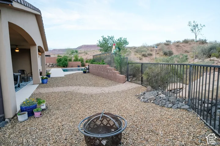 Rear exterior featuring a covered patio with an outdoor fan, a swimming pool, and a gravel landscape