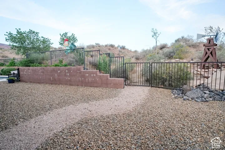 Terraced landscaping featuring a gravel pathway, block retaining wall, and black metal fencing