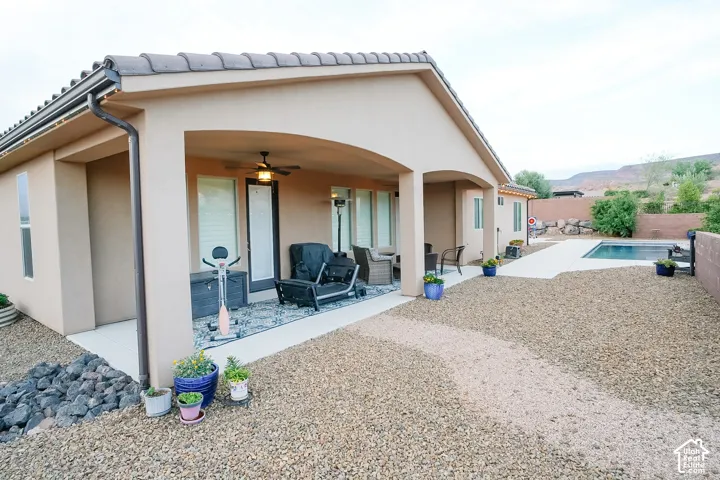 Expansive xeriscaped backyard featuring a covered patio, paved walkway, and an in-ground swimming pool
