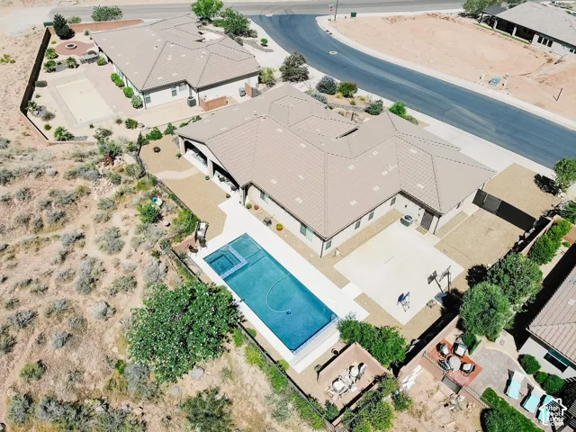 Expansive property featuring a large swimming pool with an integrated spa, extensive hardscaping, and a mature tree line