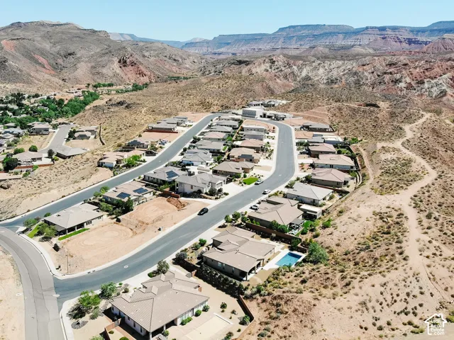 Residential development featuring a winding street, multiple single-story homes with tile roofs, and a backdrop of desert mountains