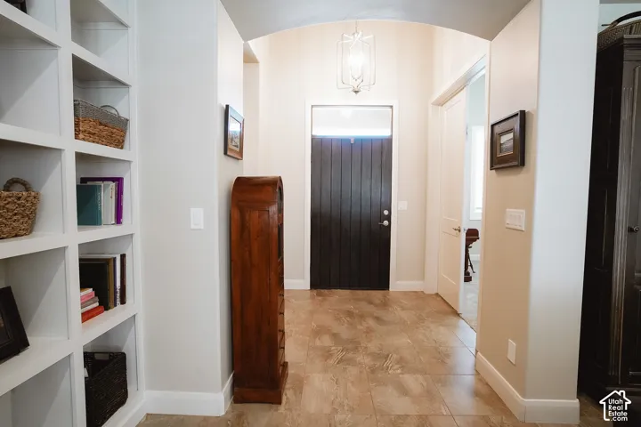 Entryway featuring a dark wood-finish door with transom window, tile flooring, built-in shelving, and archway architectural detail