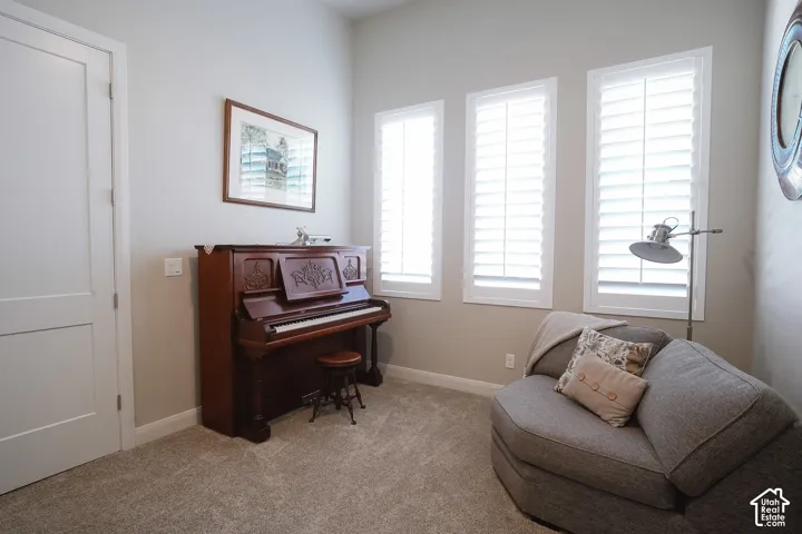 Room featuring neutral wall tones, three tall windows with white plantation shutters, and light-toned carpet flooring