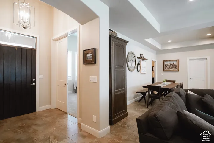 Entryway featuring a dark wood-paneled door with transom window, tile flooring, and a contemporary pendant light fixture
