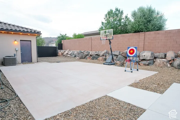 Expansive concrete patio with decorative string lighting and a durable block wall perimeter