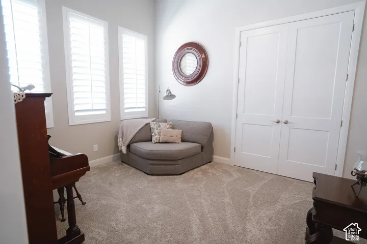 Room featuring white plantation shutters, neutral tone walls, and light-colored carpet flooring