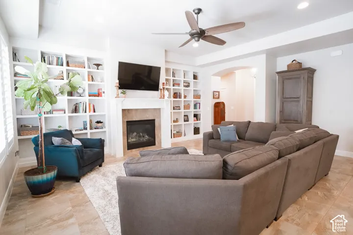 Spacious living area featuring extensive built-in shelving, a gas fireplace with a stone surround, and recessed lighting