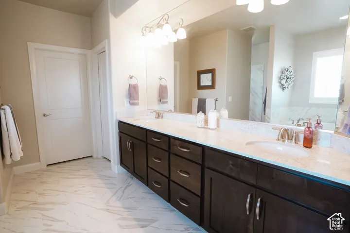 Dual vanity with dark wood cabinetry, light stone-finish countertops, and two undermount sinks