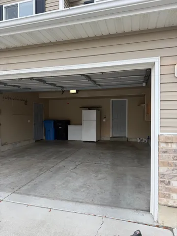 Spacious two-car garage with concrete flooring, finished walls, and an overhead light fixture