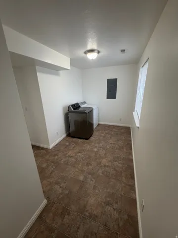 Dedicated utility area featuring tile-patterned flooring and a window with blinds