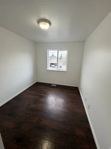 Neutral interior featuring dark wood-finish flooring and white baseboards