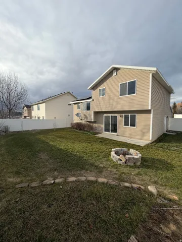 Rear exterior featuring tan horizontal siding, white trim, and a white privacy fence