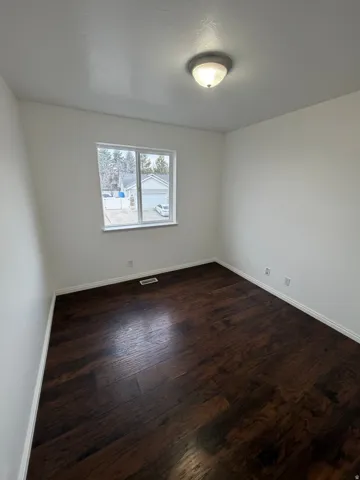 Bright interior space featuring a window, dark wood-finish flooring, white baseboards, and a semi-flush mount ceiling light fixture