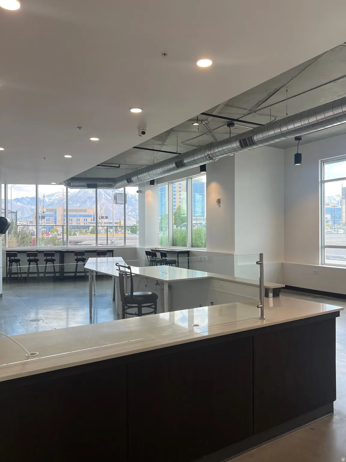 Open-concept space featuring extensive counter seating, multiple work surfaces, recessed ceiling lighting, exposed ductwork, and abundant natural light from numerous windows