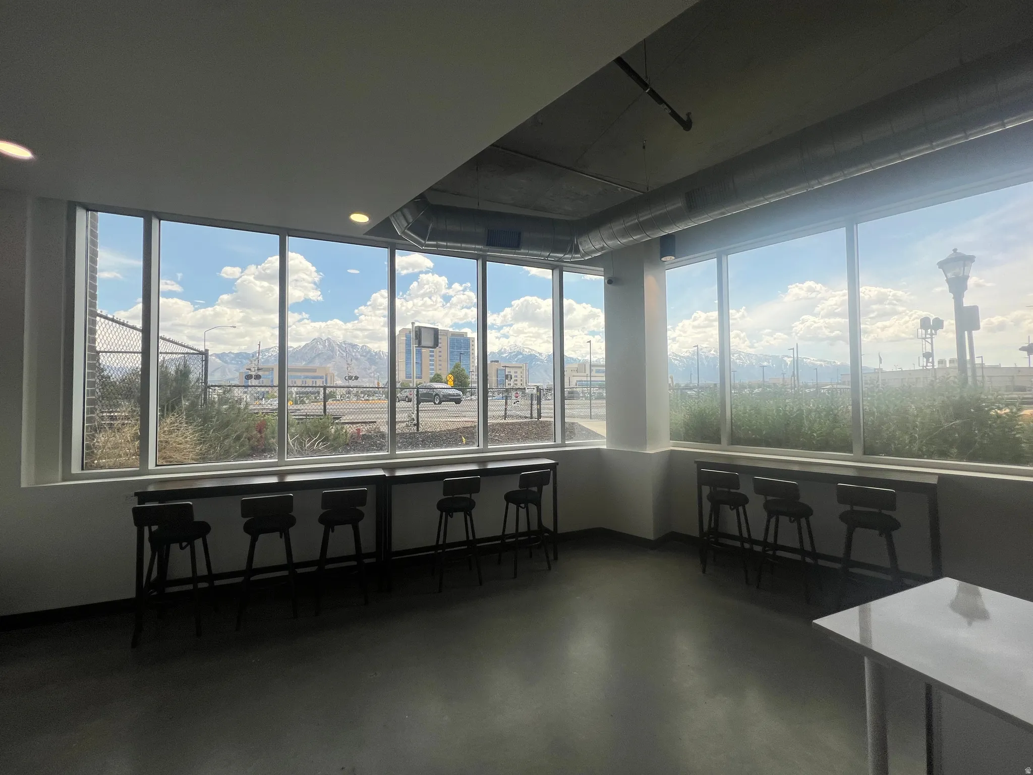 Expansive floor-to-ceiling windows with mountain scenery, concrete-finish flooring, exposed ductwork, and recessed lighting