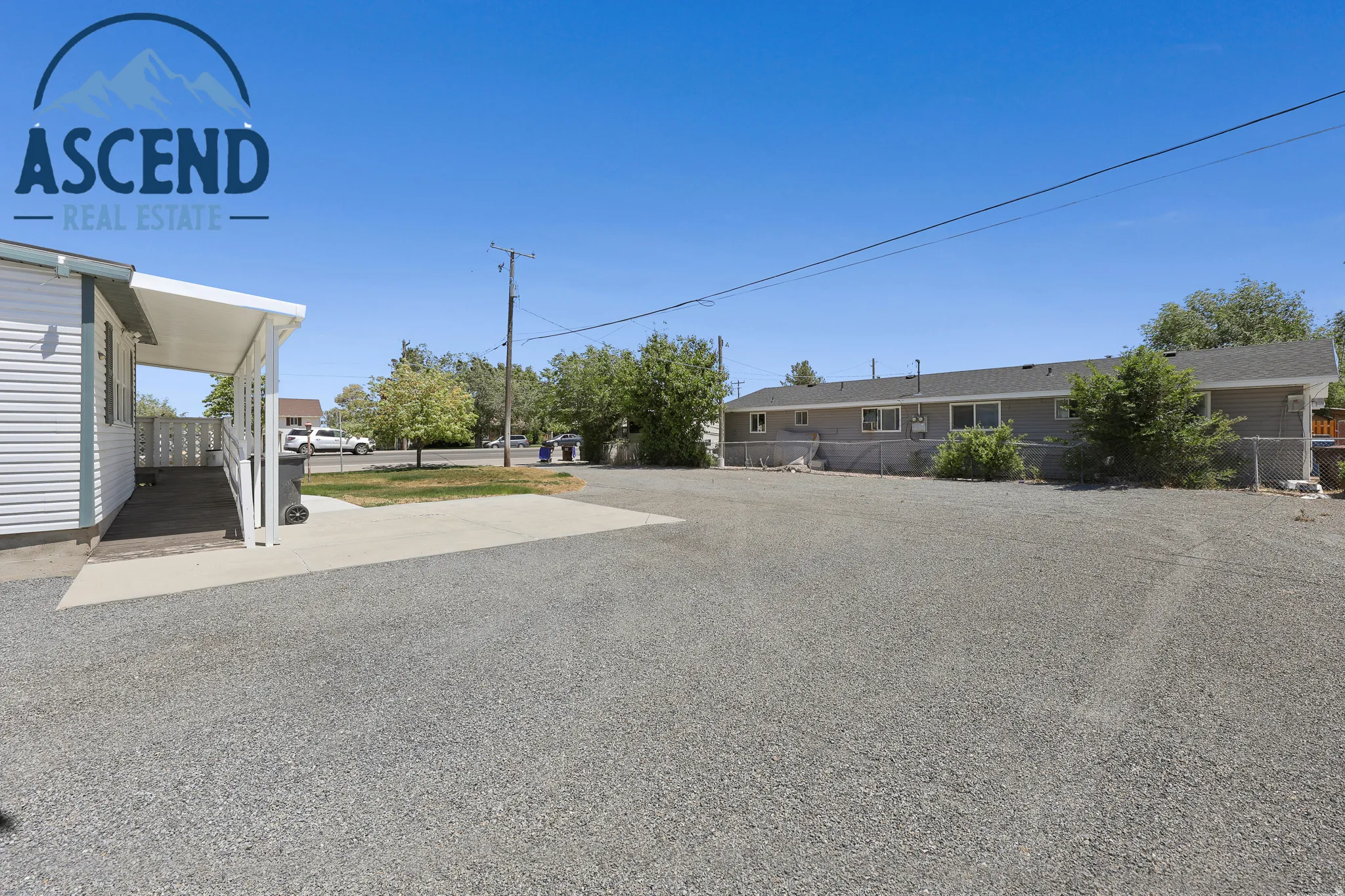 Gravel parking area offering extensive paved access and a covered ramp entry to the side door.