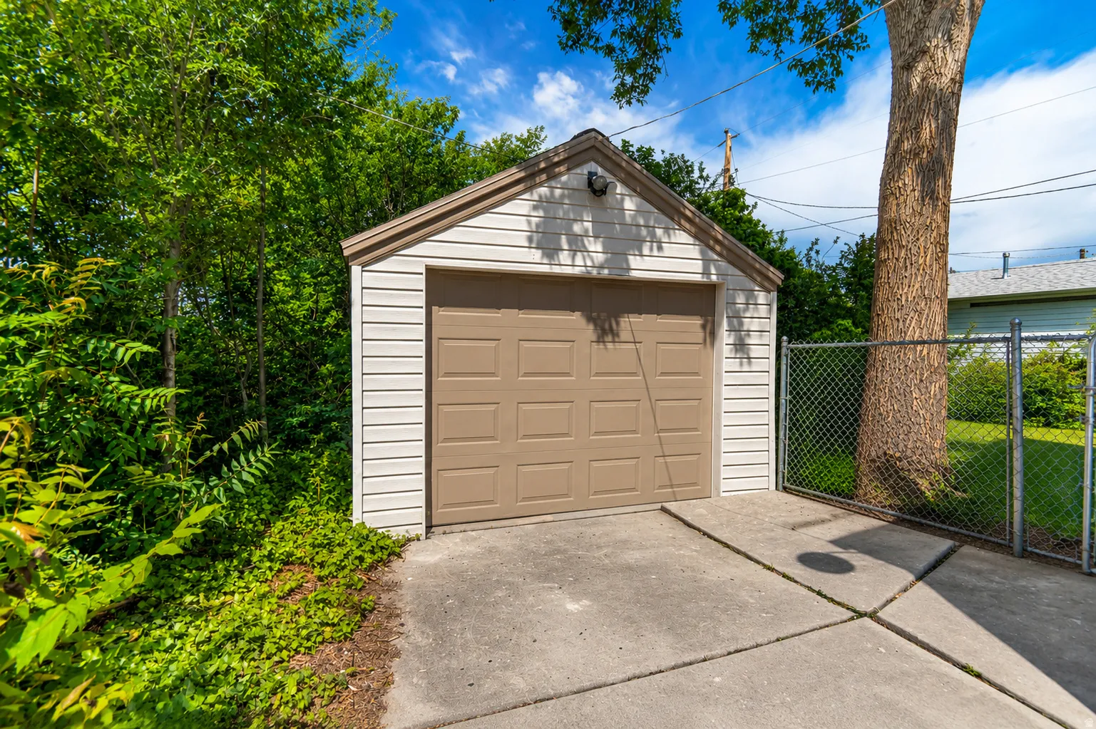 Detached garage featuring horizontal siding and a panel-style door, complemented by a concrete driveway
