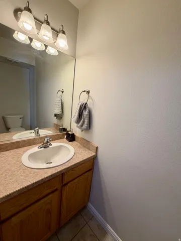 Bathroom vanity featuring a speckled countertop, a drop-in sink with a chrome faucet, and wood-finish cabinetry