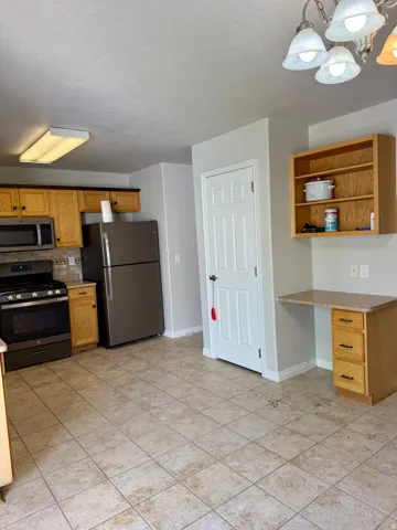 Kitchen featuring wood cabinetry, stainless steel appliances, and tile flooring