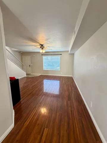 Warm wood-finish flooring throughout the main living area, complemented by a ceiling fan with integrated lighting