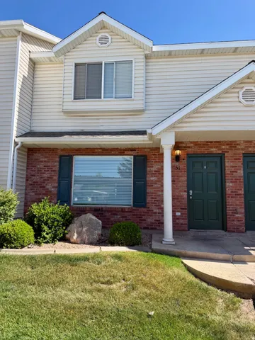 Exterior featuring brick and horizontal siding, a green entry door, and gabled architectural details