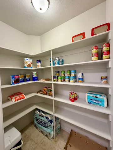Spacious corner pantry featuring multiple levels of built-in shelving, durable wood-finish flooring, and a flush mount ceiling light