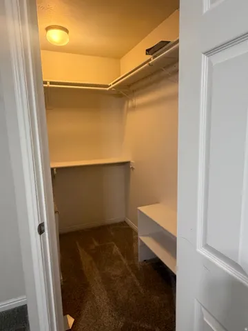 Walk-in closet featuring built-in shelving, hanging rods, an integrated storage bench, and recessed ceiling lighting