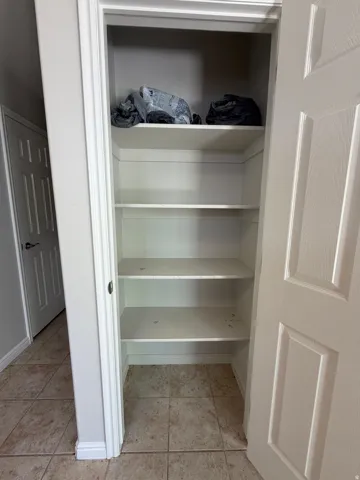 Built-in storage closet featuring multiple shelves and a tiled floor