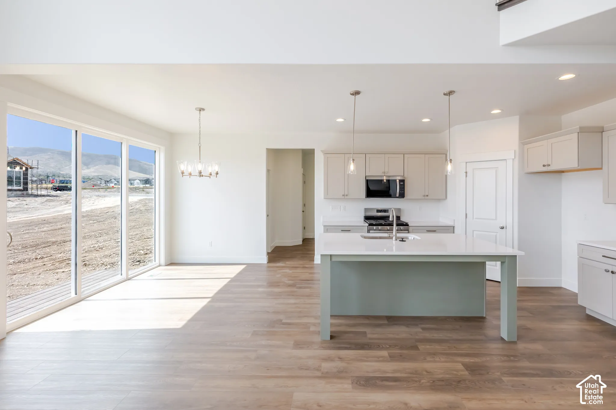 Open-concept main level featuring wood-finish flooring, a contemporary chandelier, and large sliding glass doors