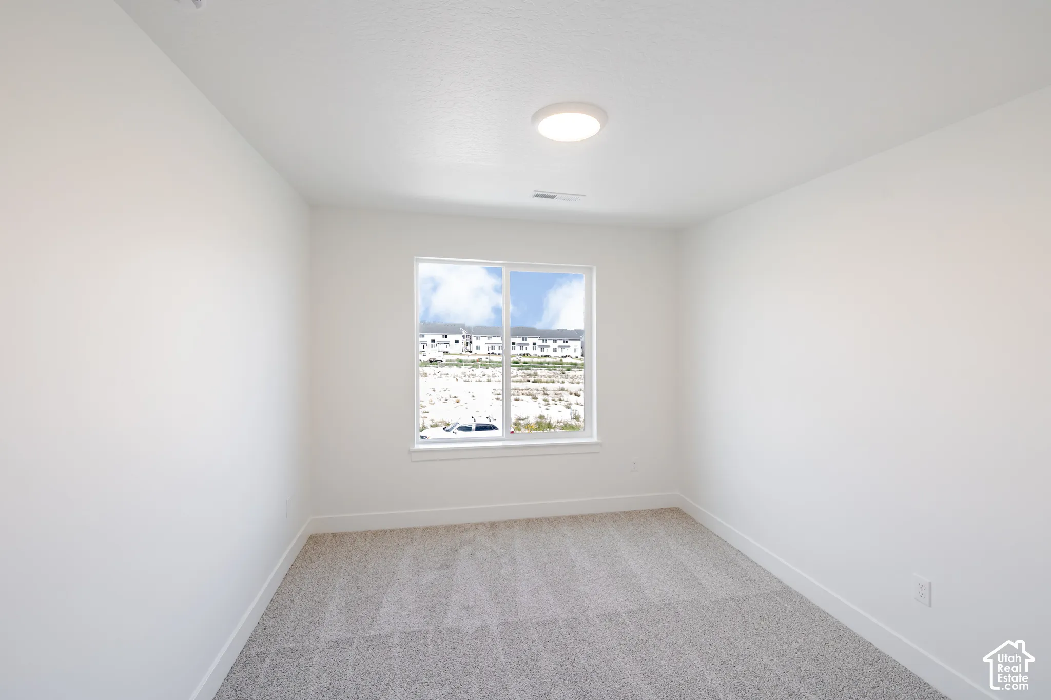 Recessed window with white trim, gray patterned carpet, and a flush-mount ceiling light