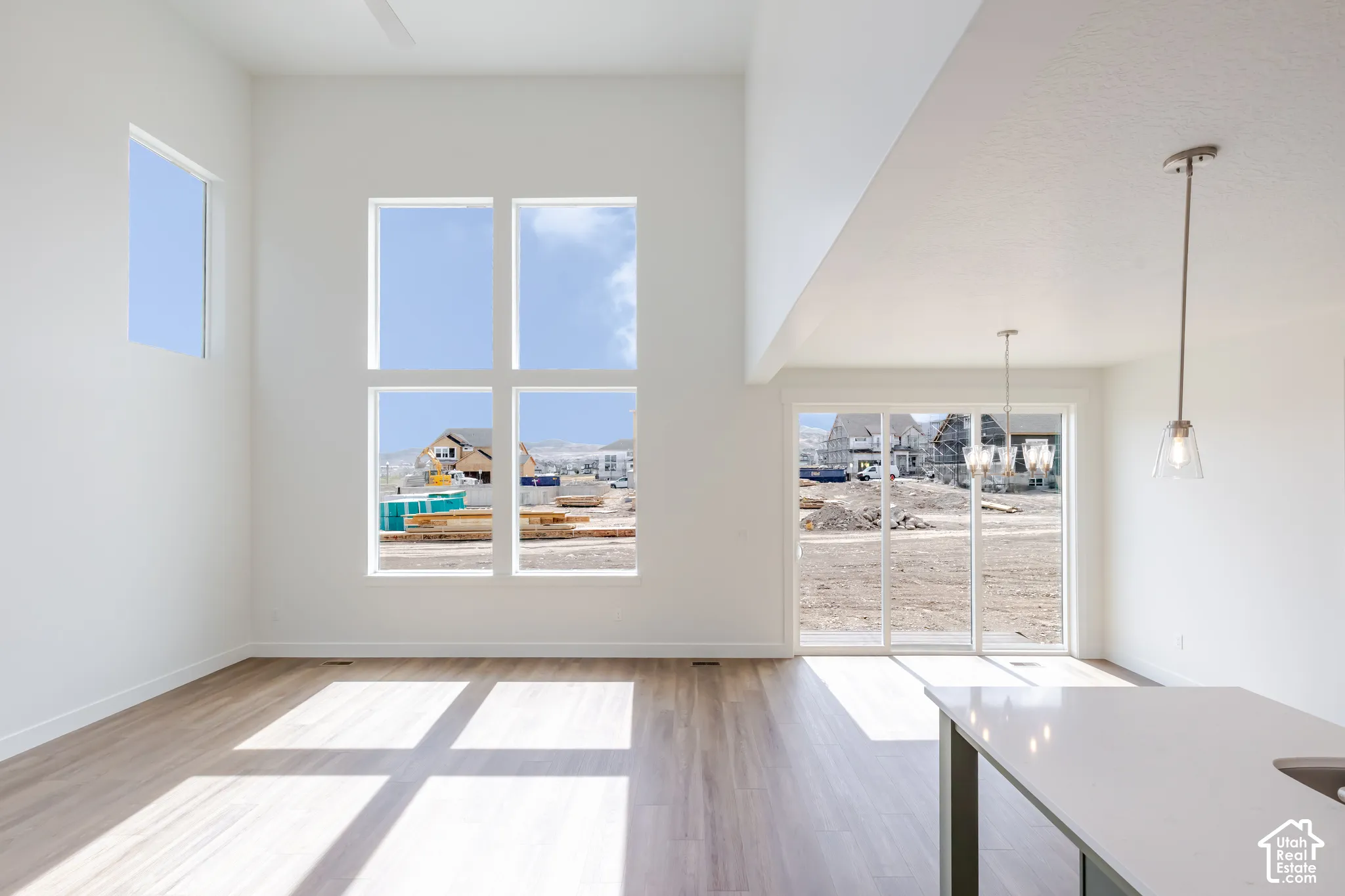 High ceilings, wood-finish flooring, multiple large windows, sliding glass door, and a white quartz-topped island