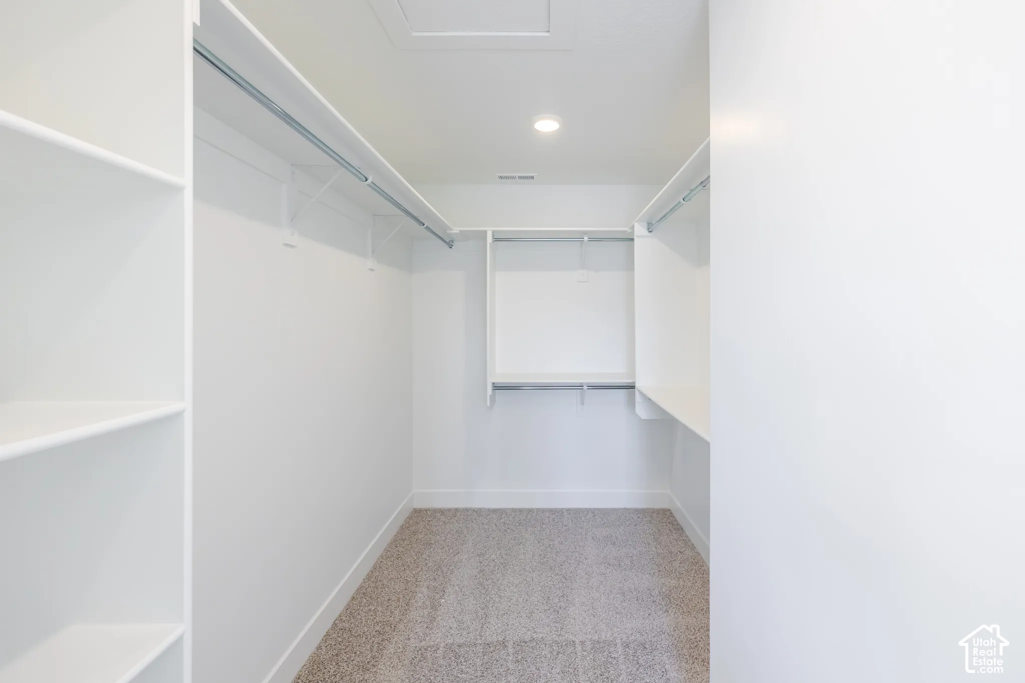 Spacious walk-in closet featuring built-in shelving, multiple hanging rods, and recessed lighting